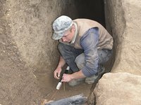 Das Foto zeigt das Mundloch eines kleinen Stollens in Shashkoc/Šaškovac im Kosovo. Ein Mitarbeiter legt gerade ein altes Ausbauholz frei, das direkt vor dem Mundloch lag.